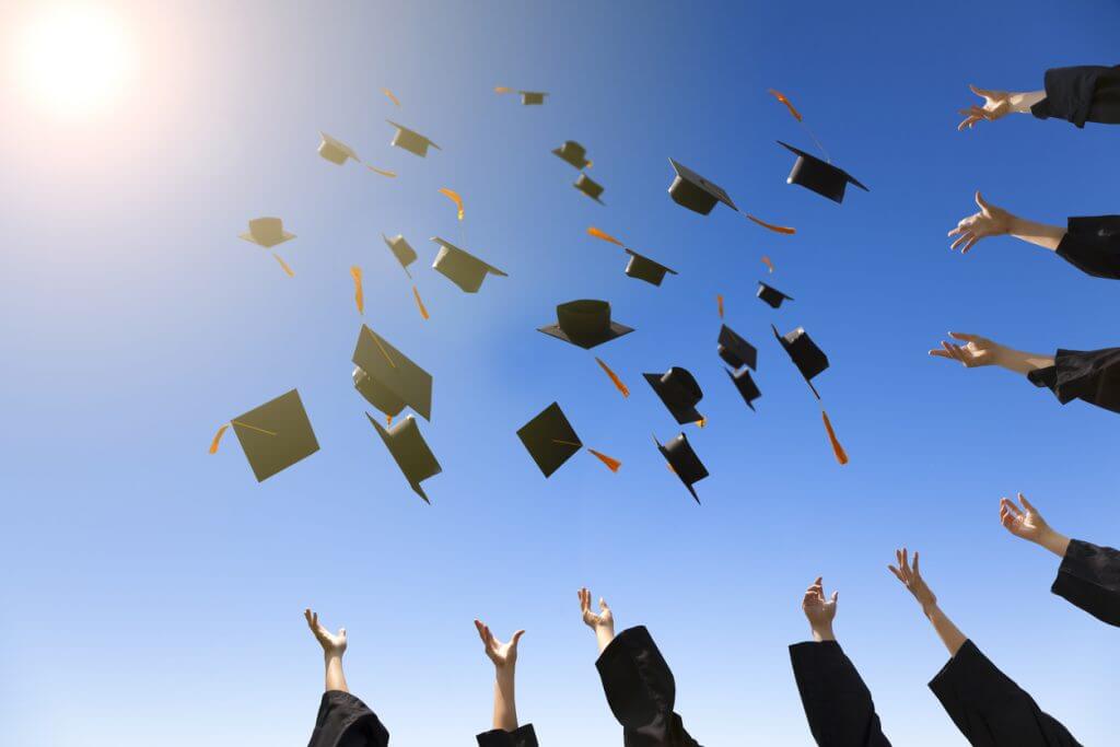 Bachelorabsolventen werfen Ihre Hüte in die Luft