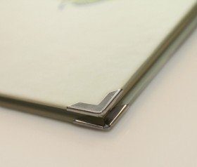 Sie können Ihre Hardcover-Cocktailkarte mit Buchecken aufwerten. Hier sehen die die kleine Grüße in Silber, die schützt und ein stilvolles Designelement setzt.